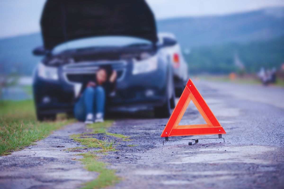 automobile ferma con ragazza seduta e triangolo