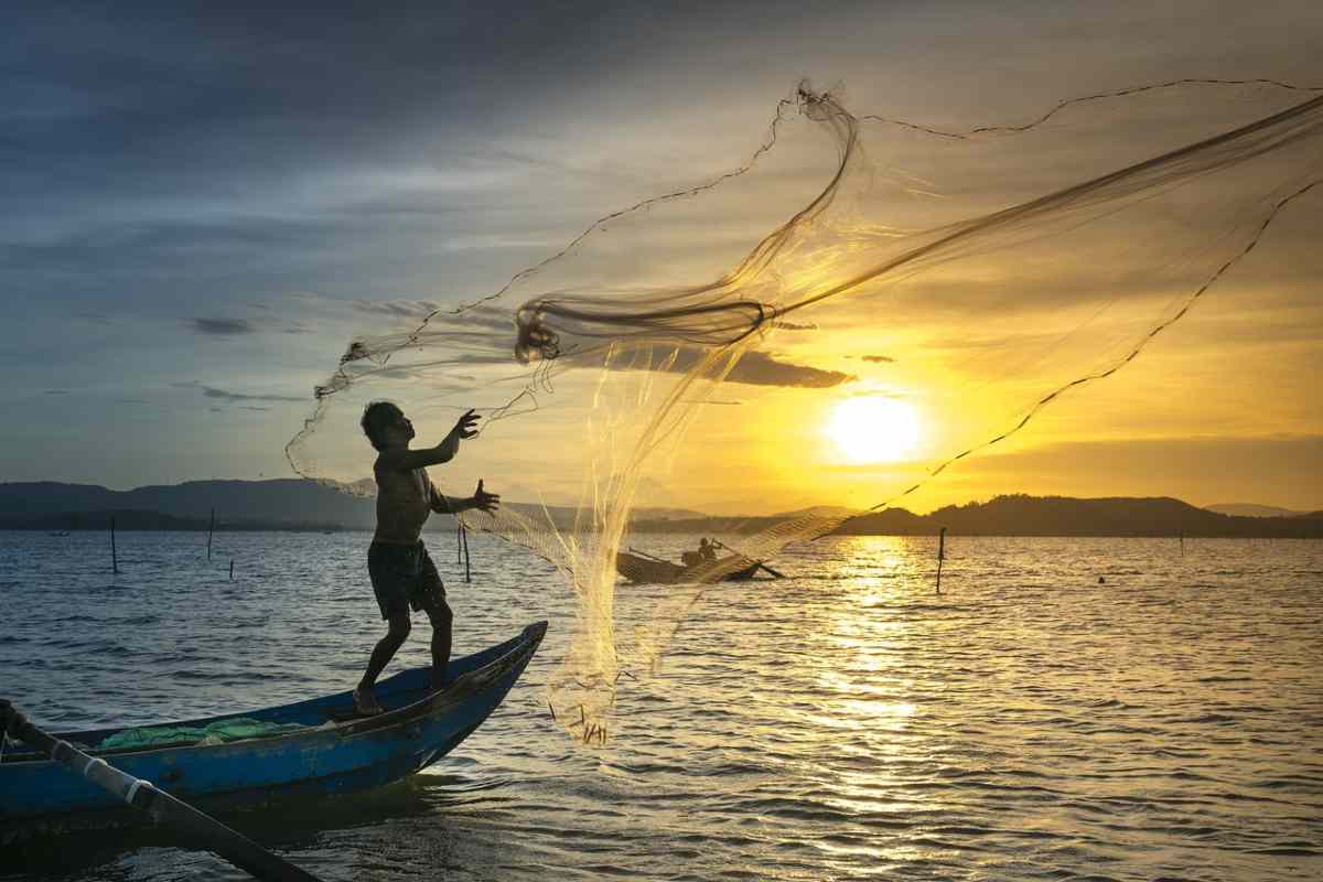 Pescatore getta una rete in mare